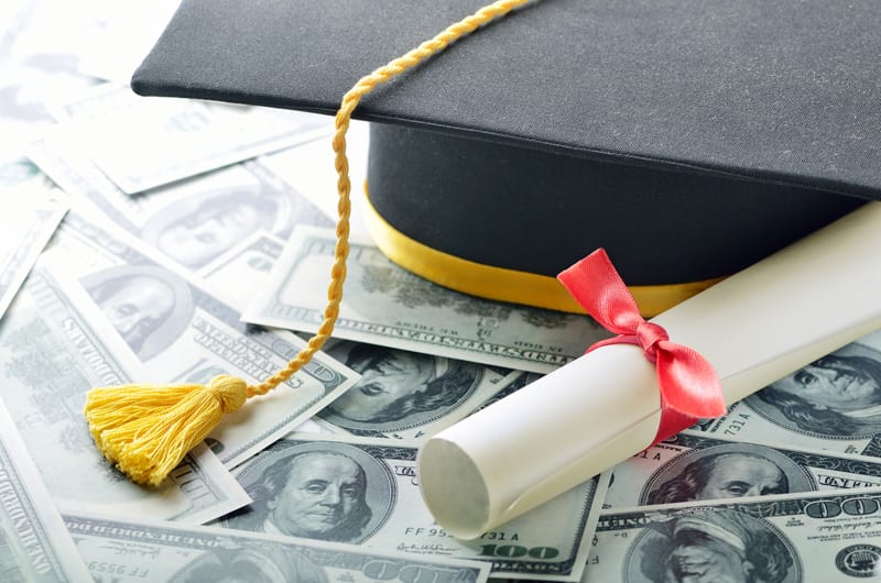 Student-Loans-Payoff Graduation cap on stack of money